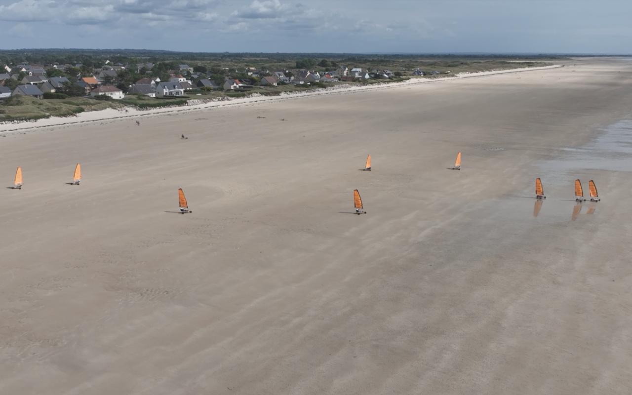 Char à voile naviguant au coucher du soleil sur la plage de Denneville - Loisirs nautiques Cotentin Manche